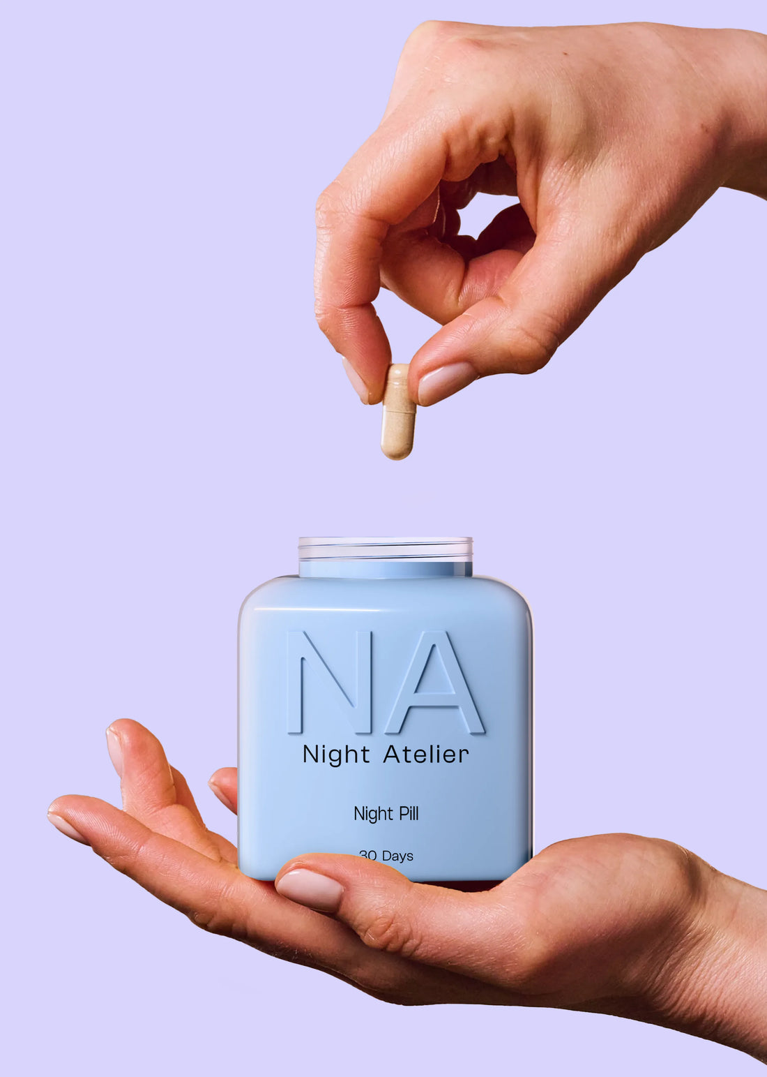 Hand holding a small container labeled 'NA Night Atelier' with a pill above it against a light purple background.
